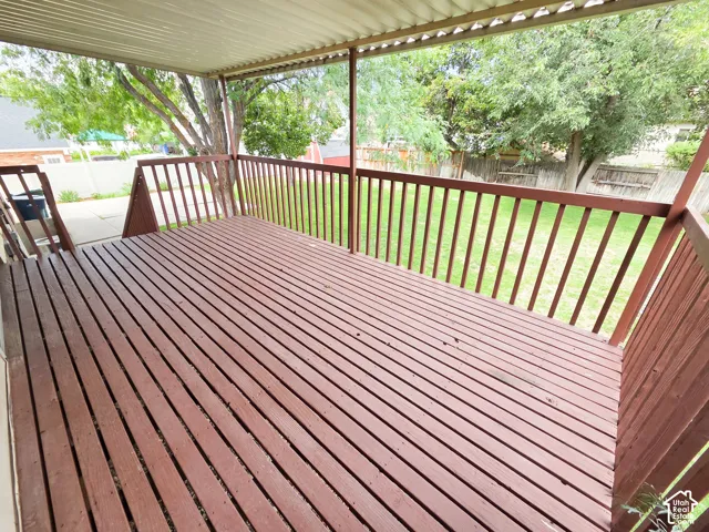 Covered wood deck with slatted wood railing and a corrugated metal ceiling