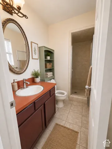Bathroom featuring a vanity with an oval sink, an oval mirror, an overhead light fixture, a built-in shower, and tile flooring