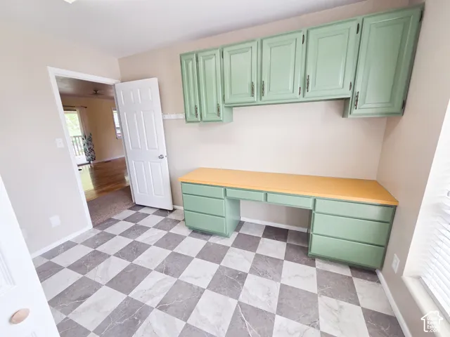 Built-in cabinetry with a light green finish, light wood-finish countertop, and checkered tile flooring