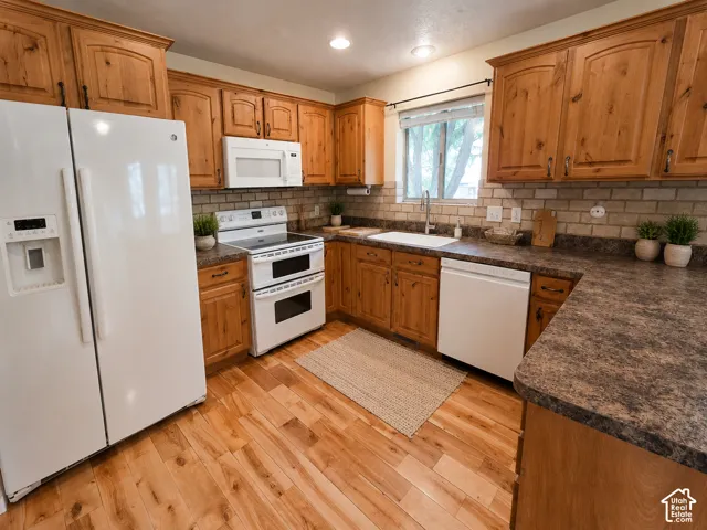 Wood-finish flooring with perimeter cabinetry, a tile backsplash, and a double oven range