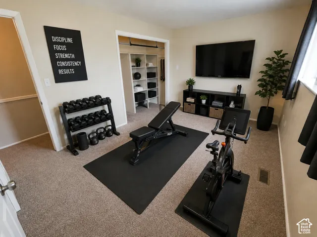 Carpeted flooring throughout, built-in shelving, mounted flat-screen media, and a wall-mounted sign