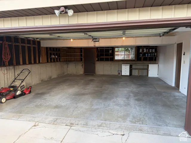 Garage space featuring a concrete floor, built-in shelving, a workbench with cabinetry, and an overhead lighting fixture