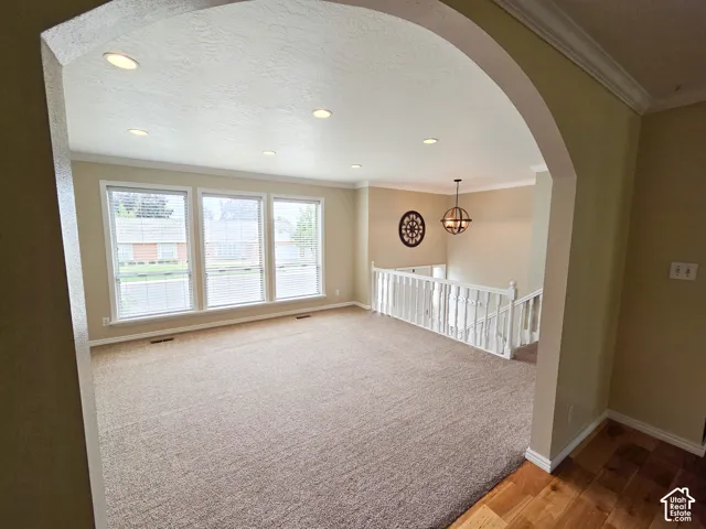 Archway entrance opening to a carpeted room with multiple windows