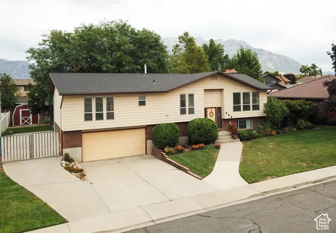 Split-level residence featuring a two-car garage, concrete driveway, and a front lawn with established landscaping
