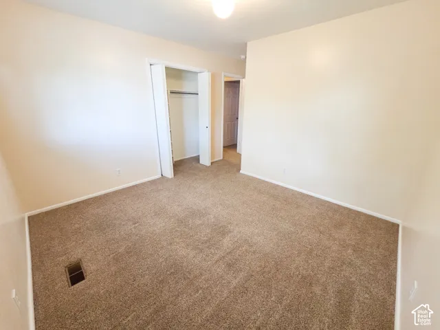 Neutral wall paint, carpet flooring, and a built-in closet with hanging rod