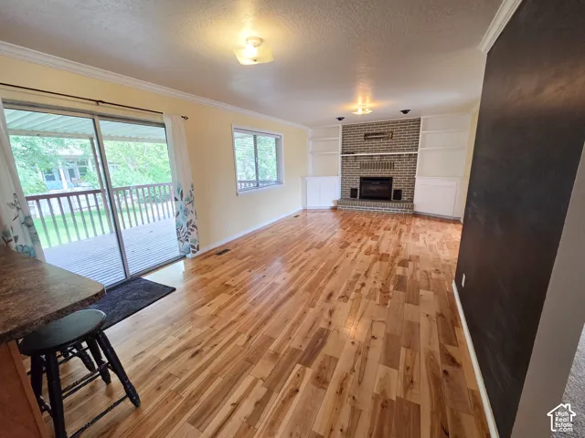 Wood-finish flooring, brick-surround fireplace with built-in shelving, sliding glass door, and overhead lighting