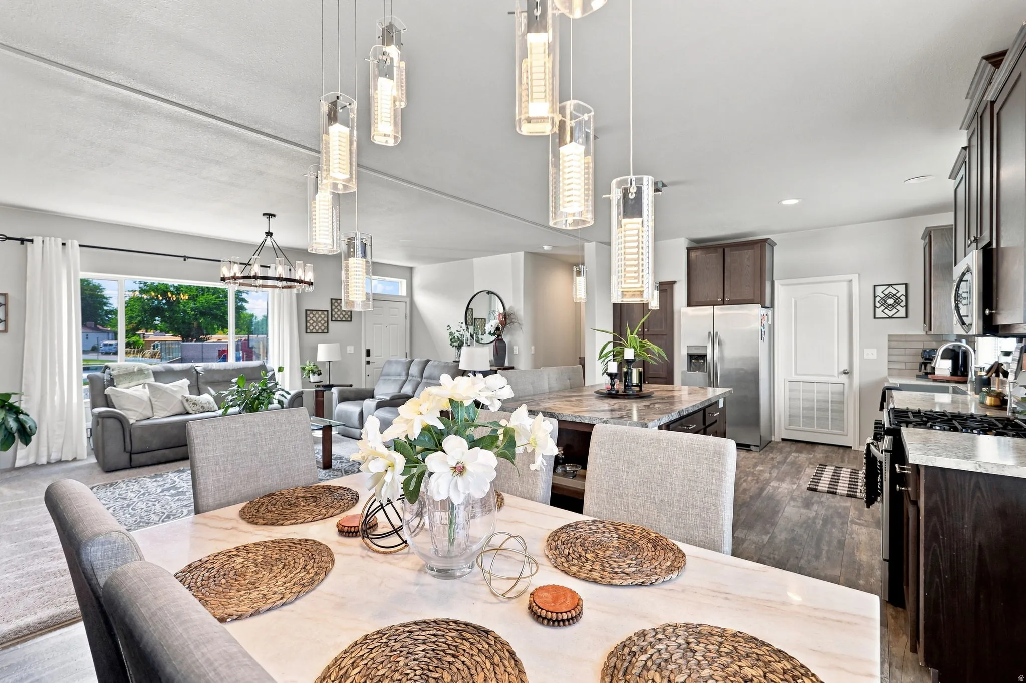 Open-concept living area with a contemporary chandelier, multiple pendant lights, and large windows