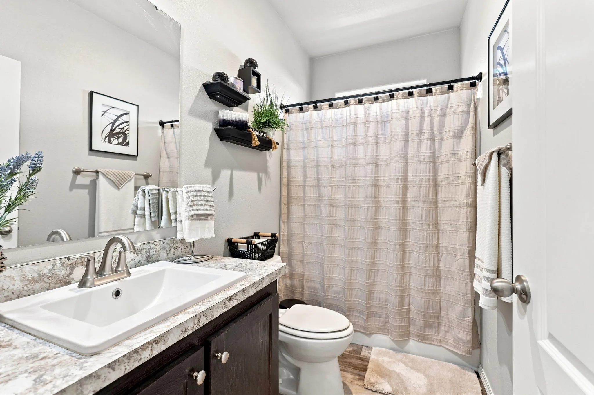 Bathroom featuring a vanity with dark wood-finish cabinetry, white integrated sink, and a framed mirror