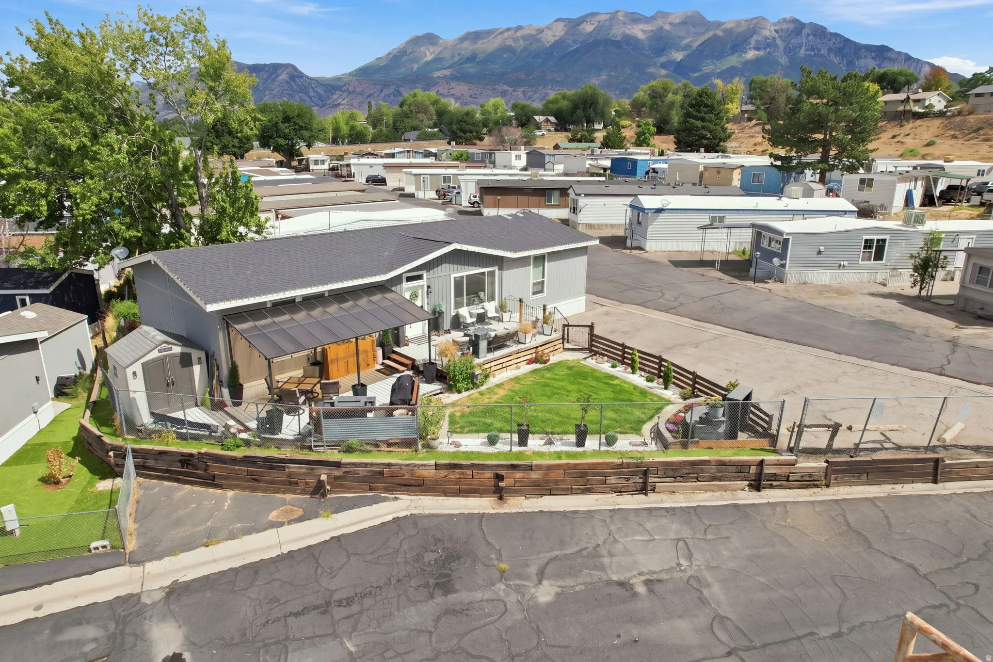 Exterior featuring gray siding, a dark roof, a covered patio, a storage shed, and a fenced yard with a manicured lawn
