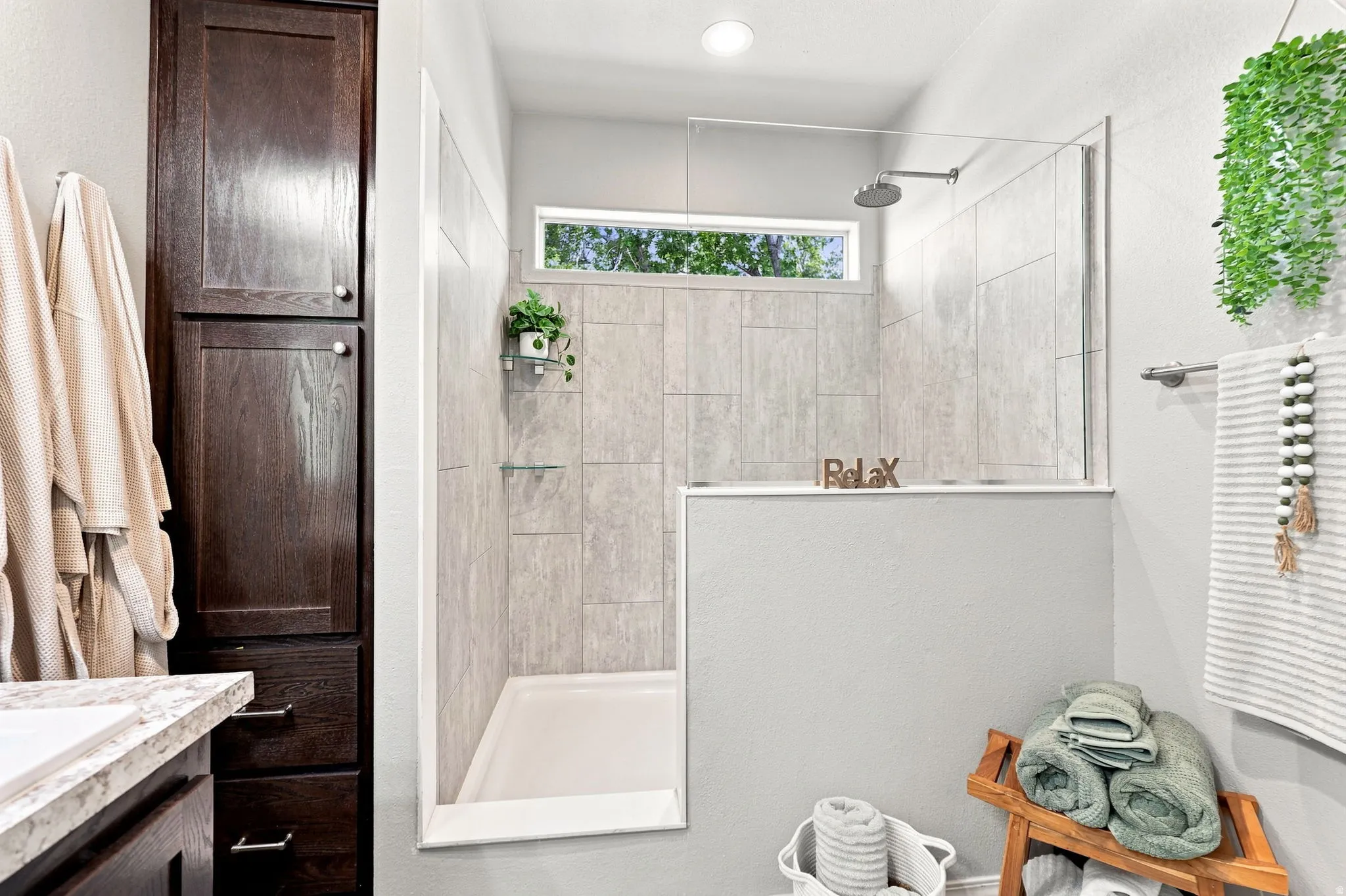Walk-in shower with tiled walls, glass enclosure, and transom window