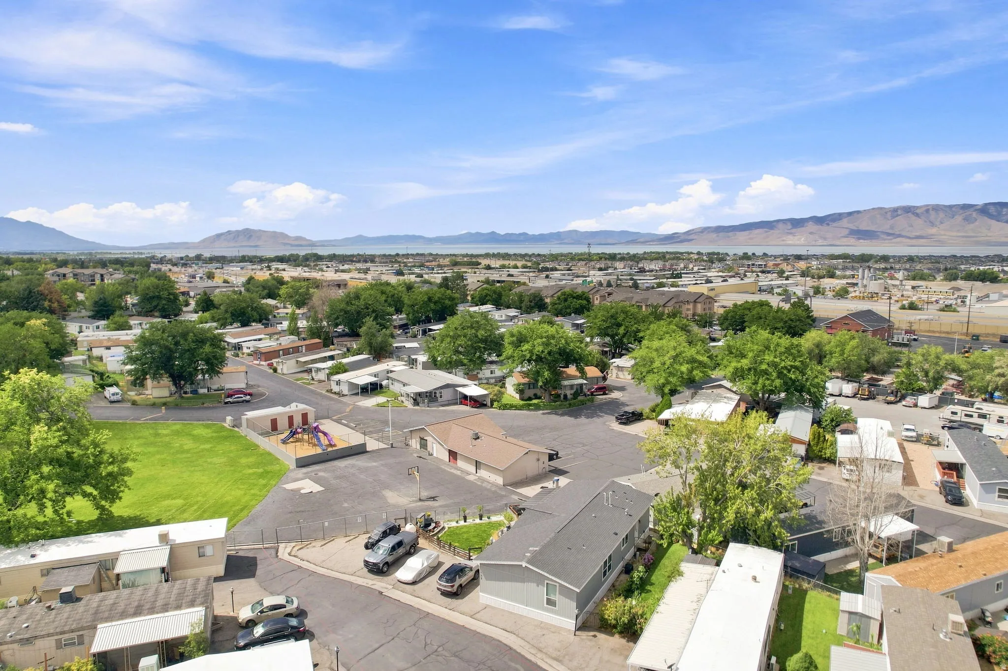 Expansive community with a large green space, playground structure, and mountain backdrop