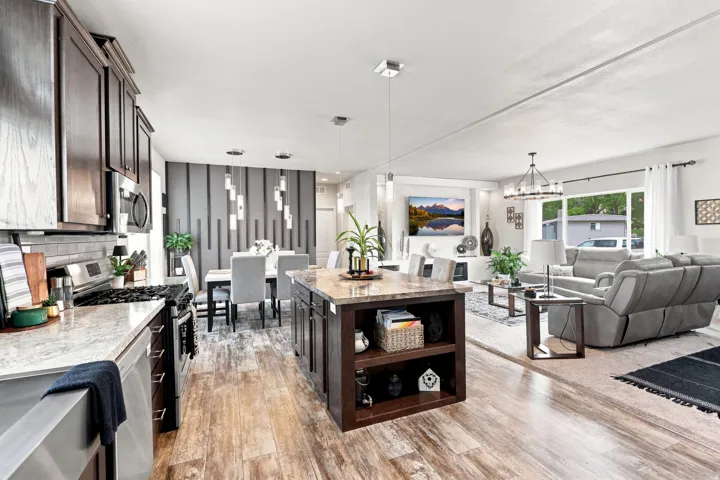 Open-concept living area featuring wood-finish flooring, a kitchen island with storage, stainless steel appliances, and a dedicated dining space with a decorative accent wall