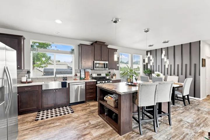 Dark wood cabinetry, stainless steel appliances, wood-finish flooring, recessed lighting, and an accent wall with vertical panels
