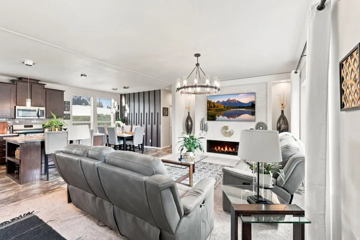 Open-concept living space featuring a linear fireplace, contemporary chandelier, and wood-finish flooring
