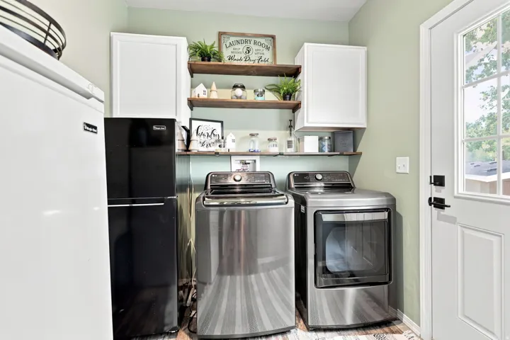 White paneled door with glass inserts, wall-mounted white cabinetry, wood-finish open shelving, and light green wall paint