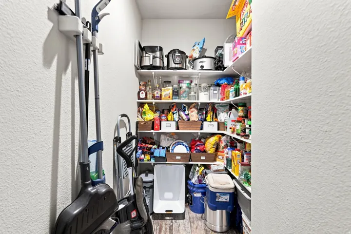 Pantry featuring built-in shelving, durable flooring, and ample storage capacity