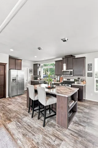 Gourmet kitchen featuring wood-finish flooring, dark wood cabinetry, stainless steel appliances, a center island with countertop, and recessed lighting