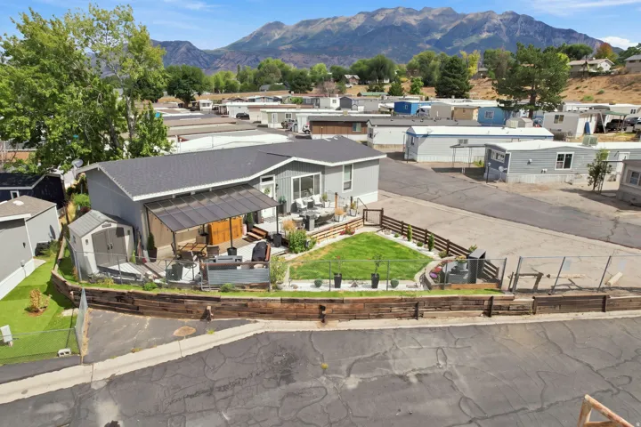 Exterior featuring gray siding, a dark roof, a covered patio, a storage shed, and a fenced yard with a manicured lawn