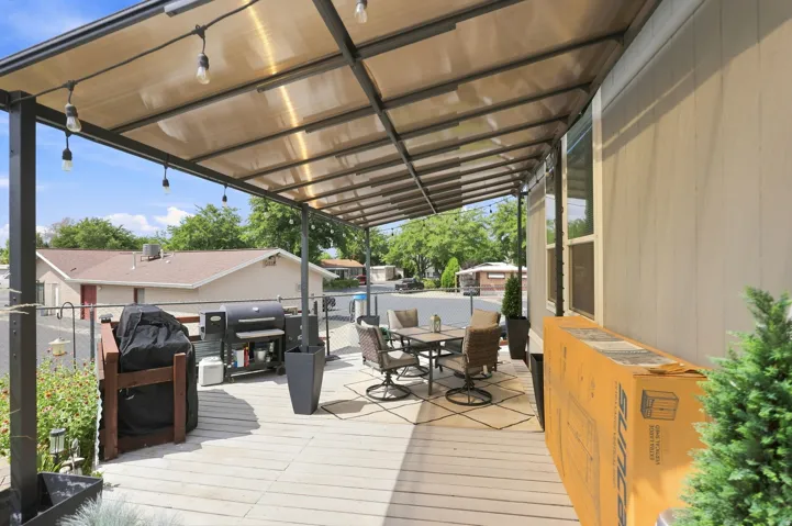 Covered outdoor deck with metal frame structure, translucent roof panels, and string lighting
