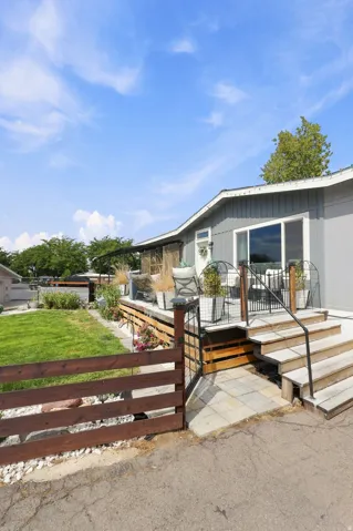 Exterior featuring a wood deck, sliding glass door, paved walkway, and wood fencing