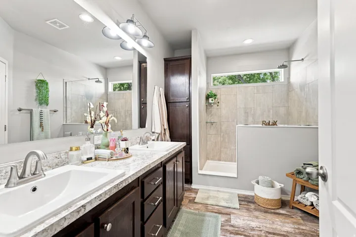 Dual sink vanity with dark wood-finish cabinetry, a large wall-mounted mirror, and overhead light fixture