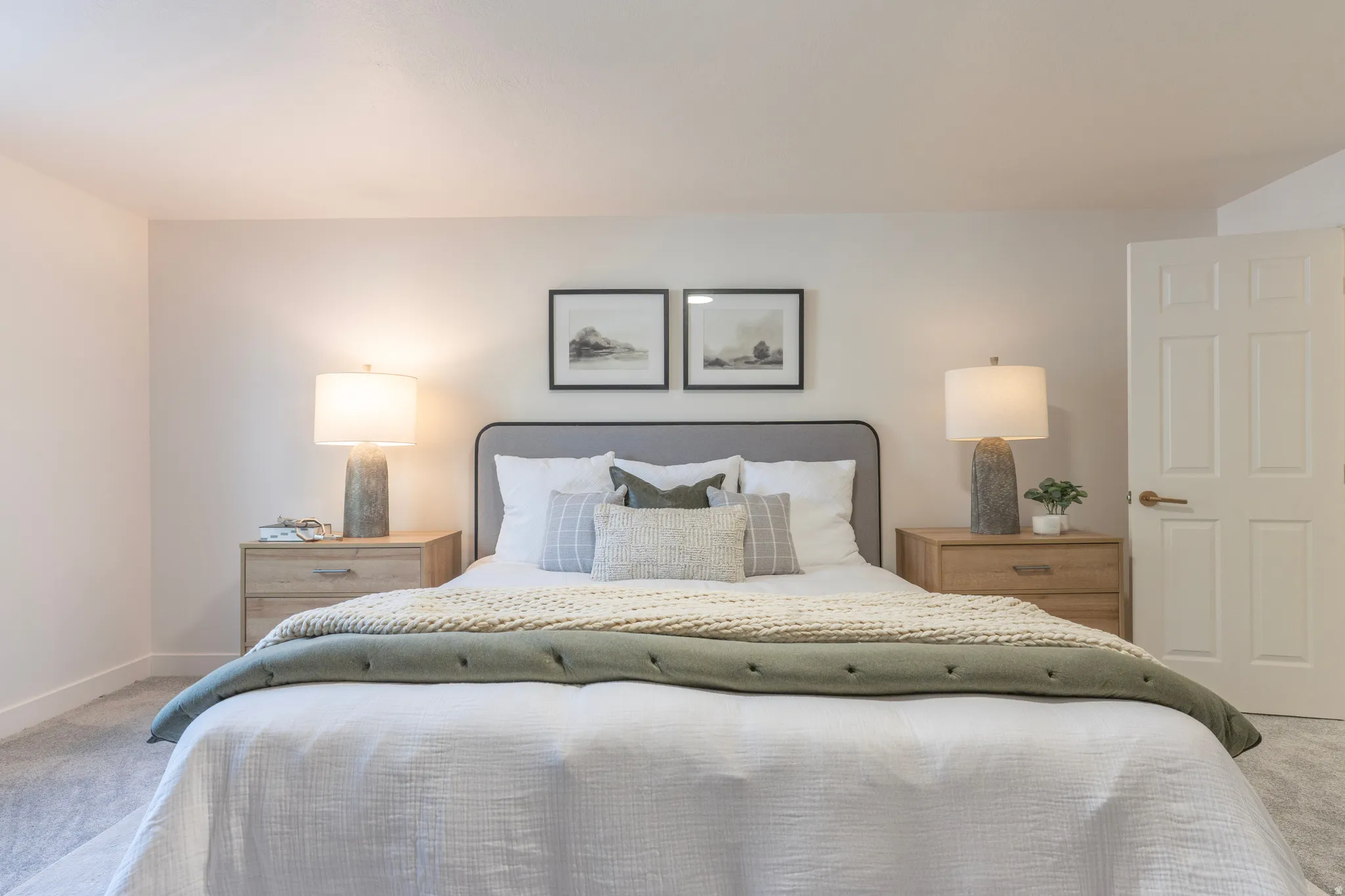Carpeted bedroom with a paneled door, light-colored walls, and a gray upholstered headboard
