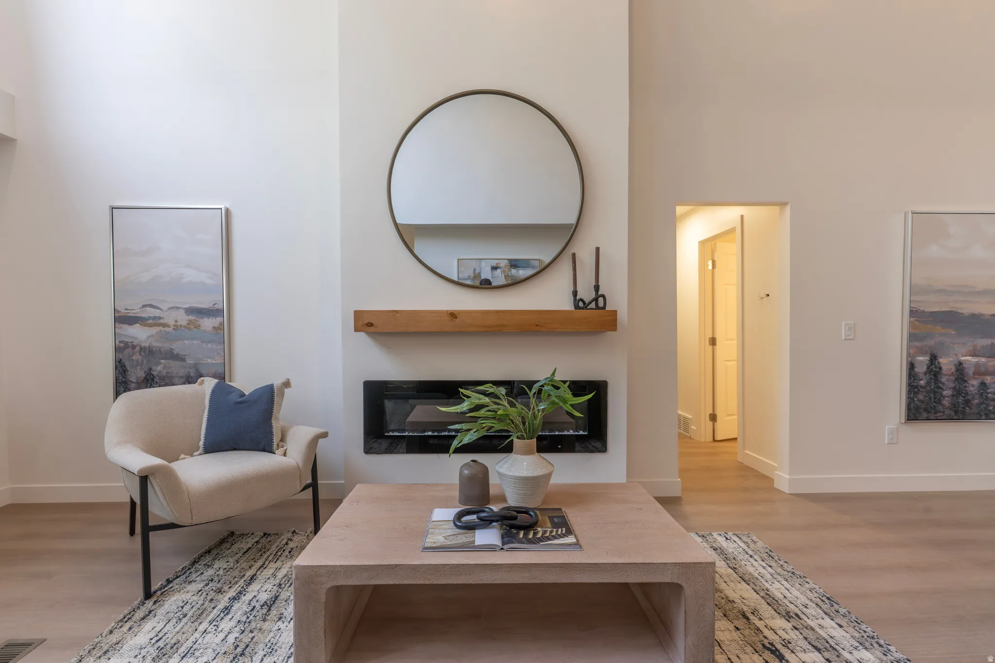 Living area featuring a floor-to-ceiling fireplace with a wood mantel, a built-in electric firebox, and wood-finish flooring
