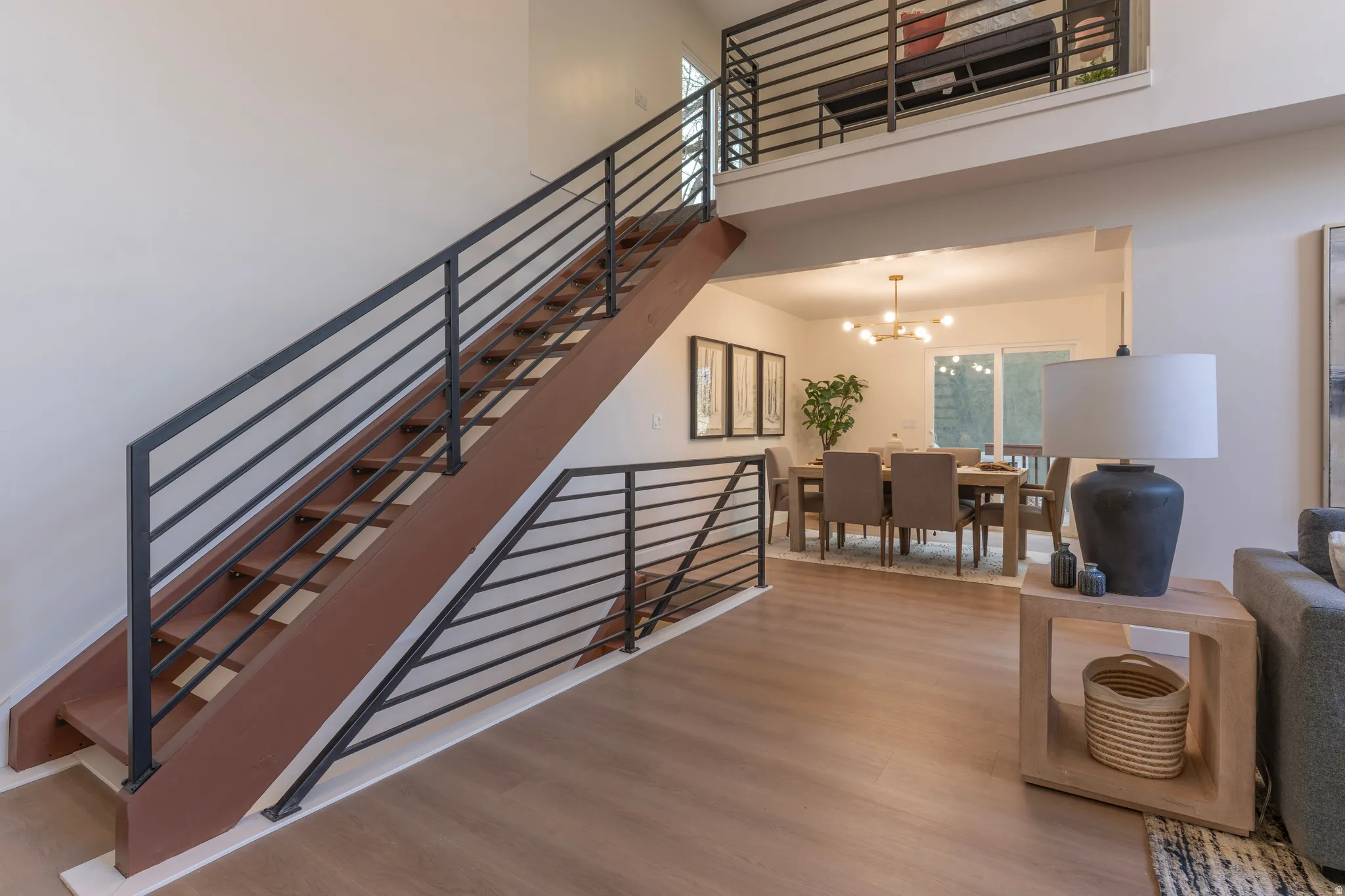 Open-concept living space featuring wood-finish flooring and a contemporary staircase with horizontal metal railings