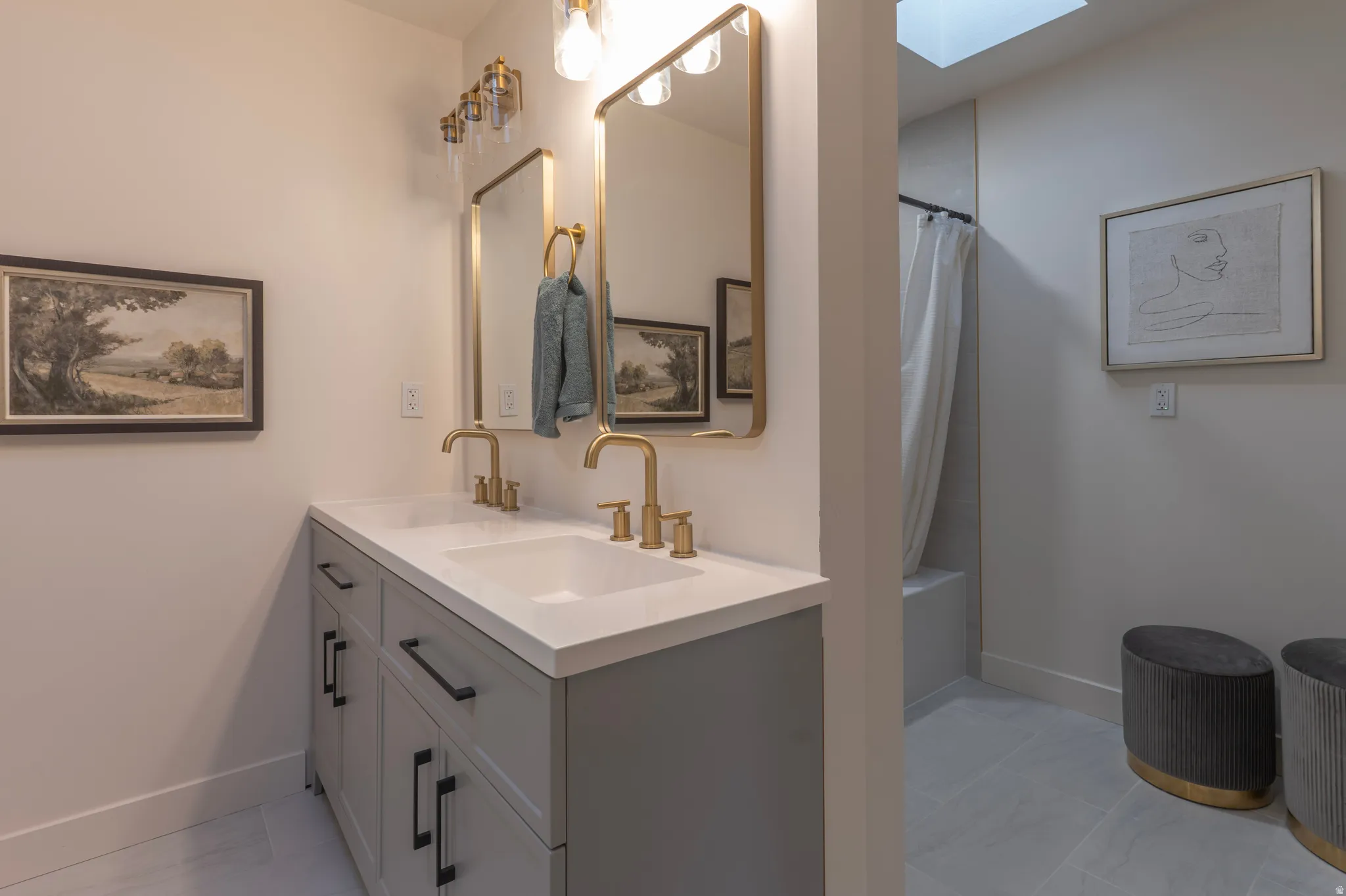 Double vanity with white countertop, gold-finish fixtures, and integrated sinks