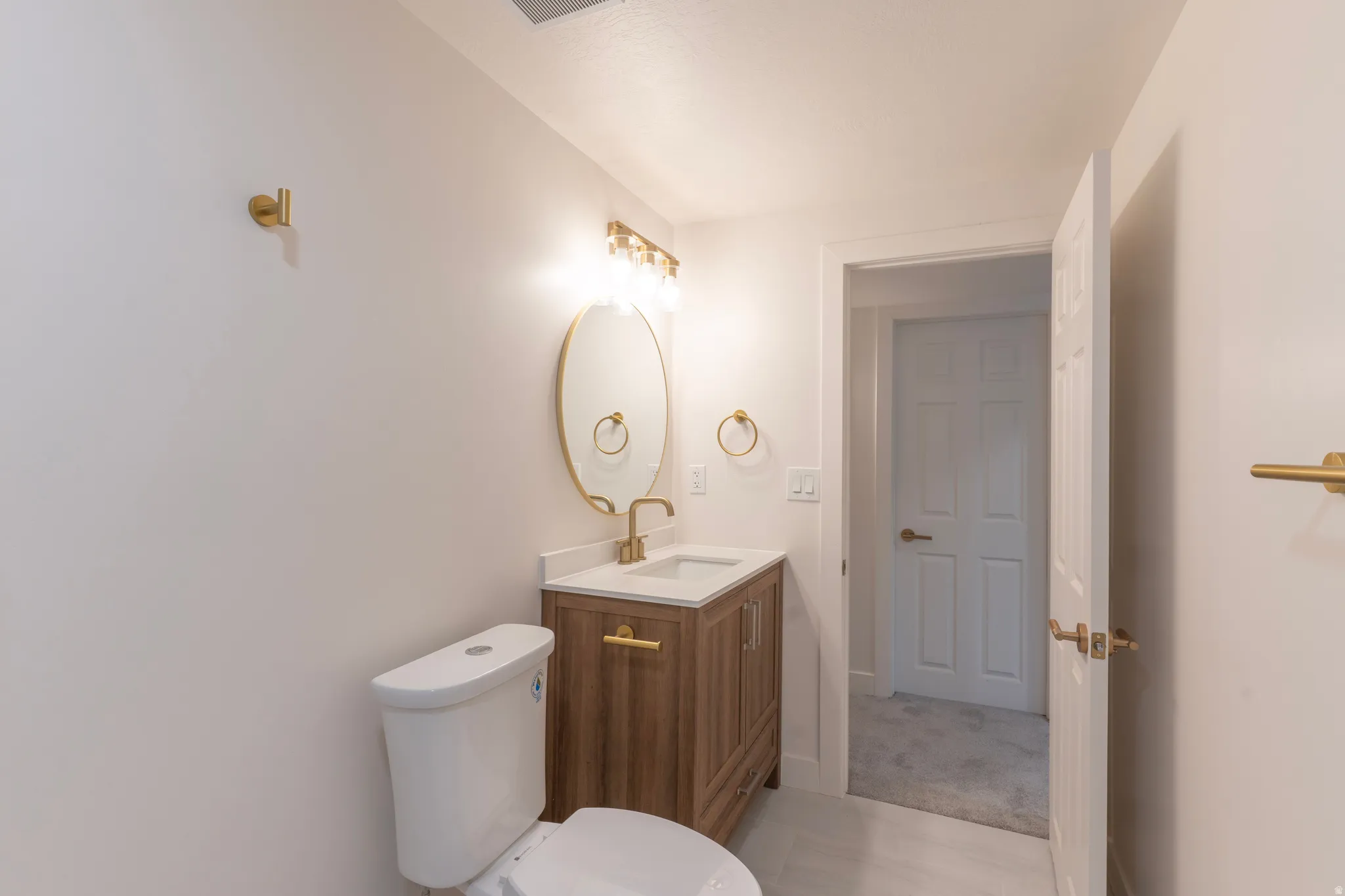 Wood-finish vanity with a white countertop and gold-tone fixtures