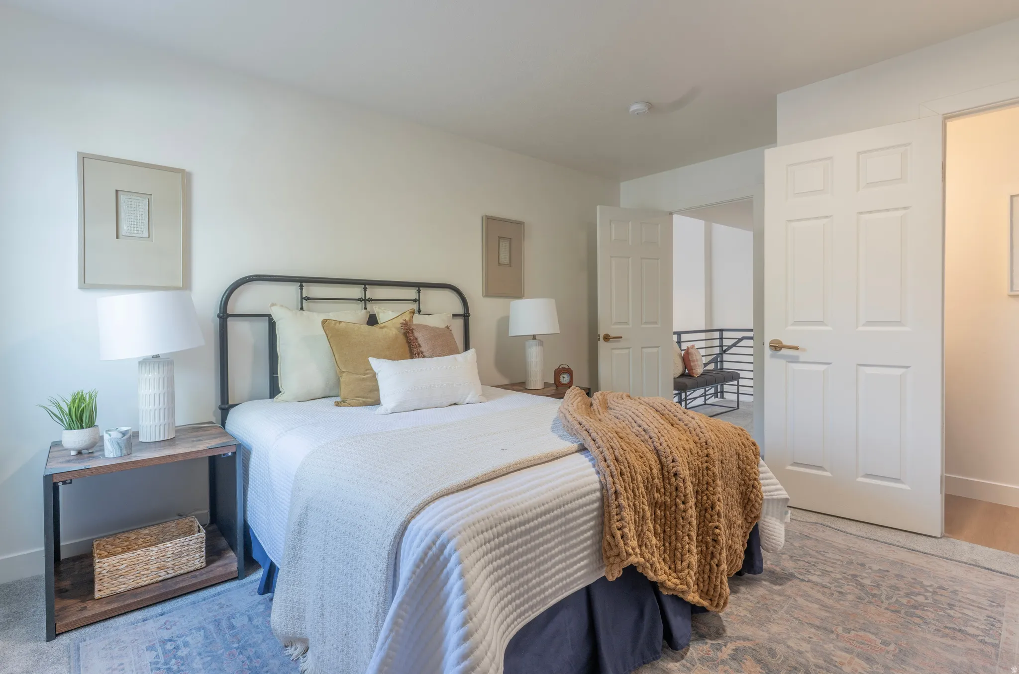 Carpeted flooring, white six-panel door, white painted walls, and an open doorway to a landing with metal railings