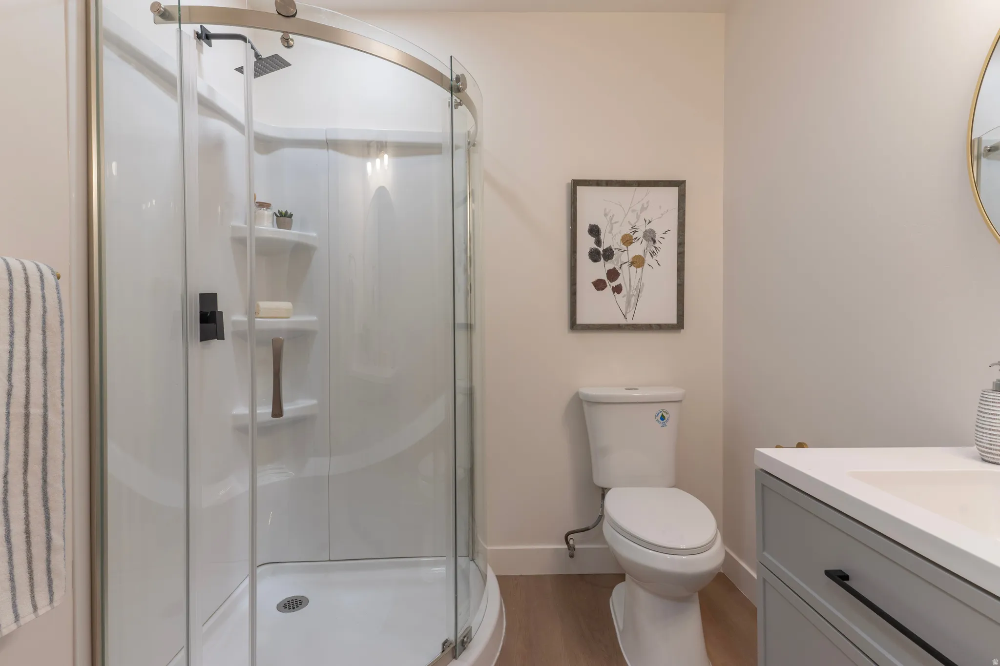 Curved glass shower enclosure with matte black fixtures, integrated shelving, and a rain showerhead