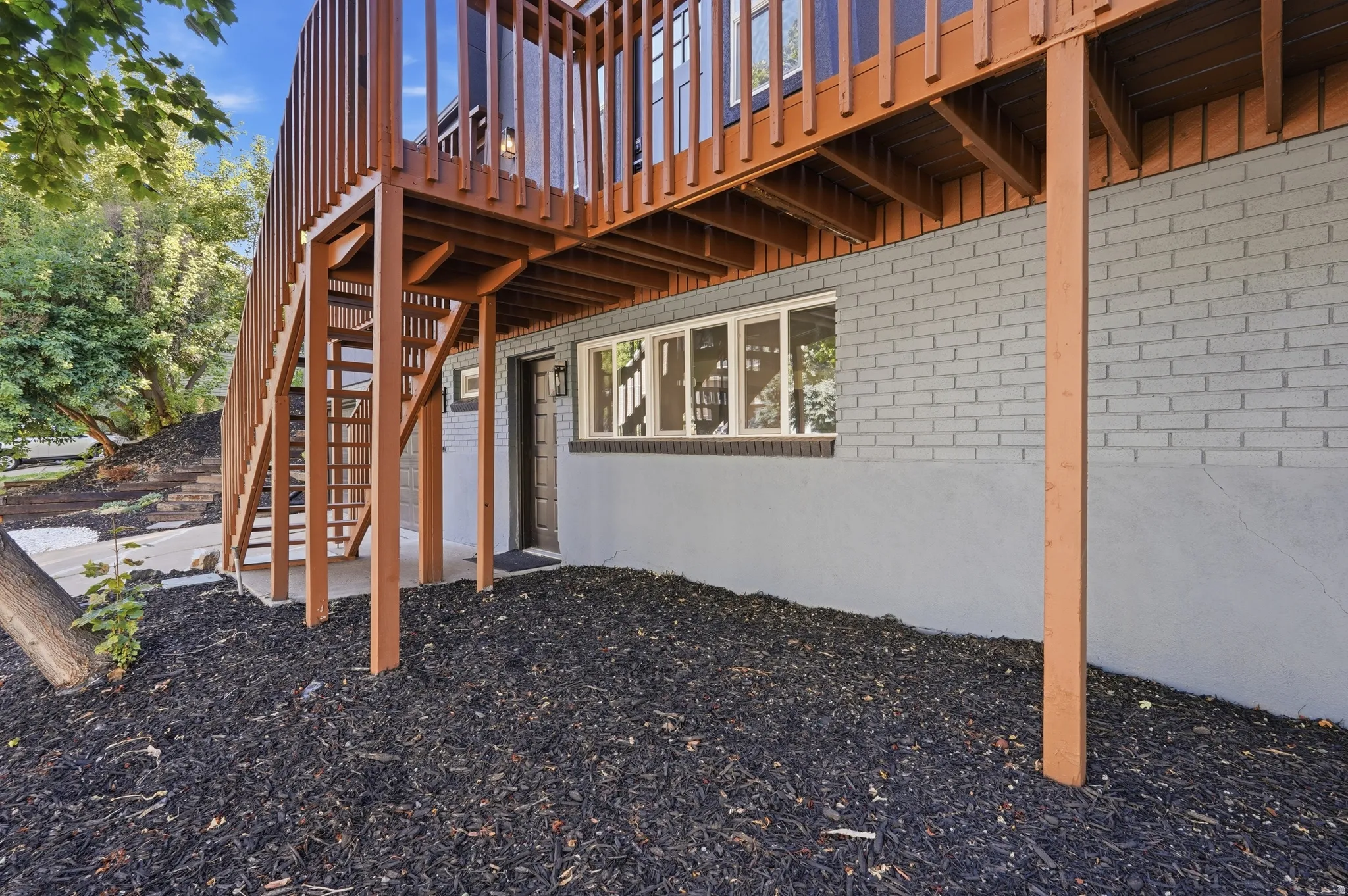 Multilevel wood deck with vertical balusters, exterior stairs, and a lower-level entry