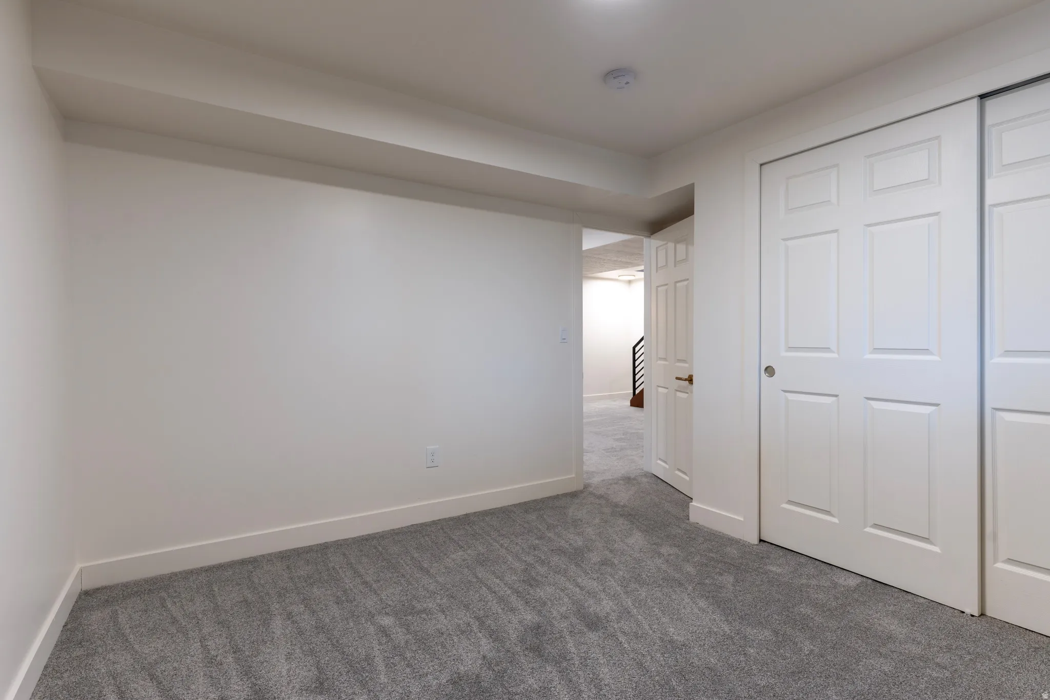 Grey carpeting with white baseboards and trim, featuring white panel doors and a white sliding closet door