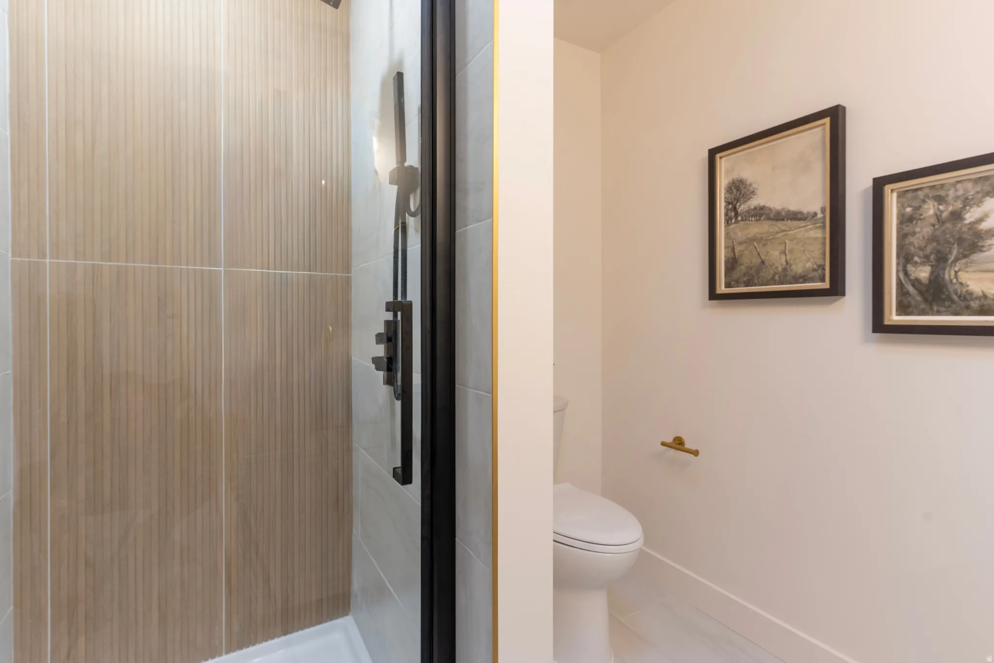 Shower enclosure with textured beige wall tile and matte black fixtures