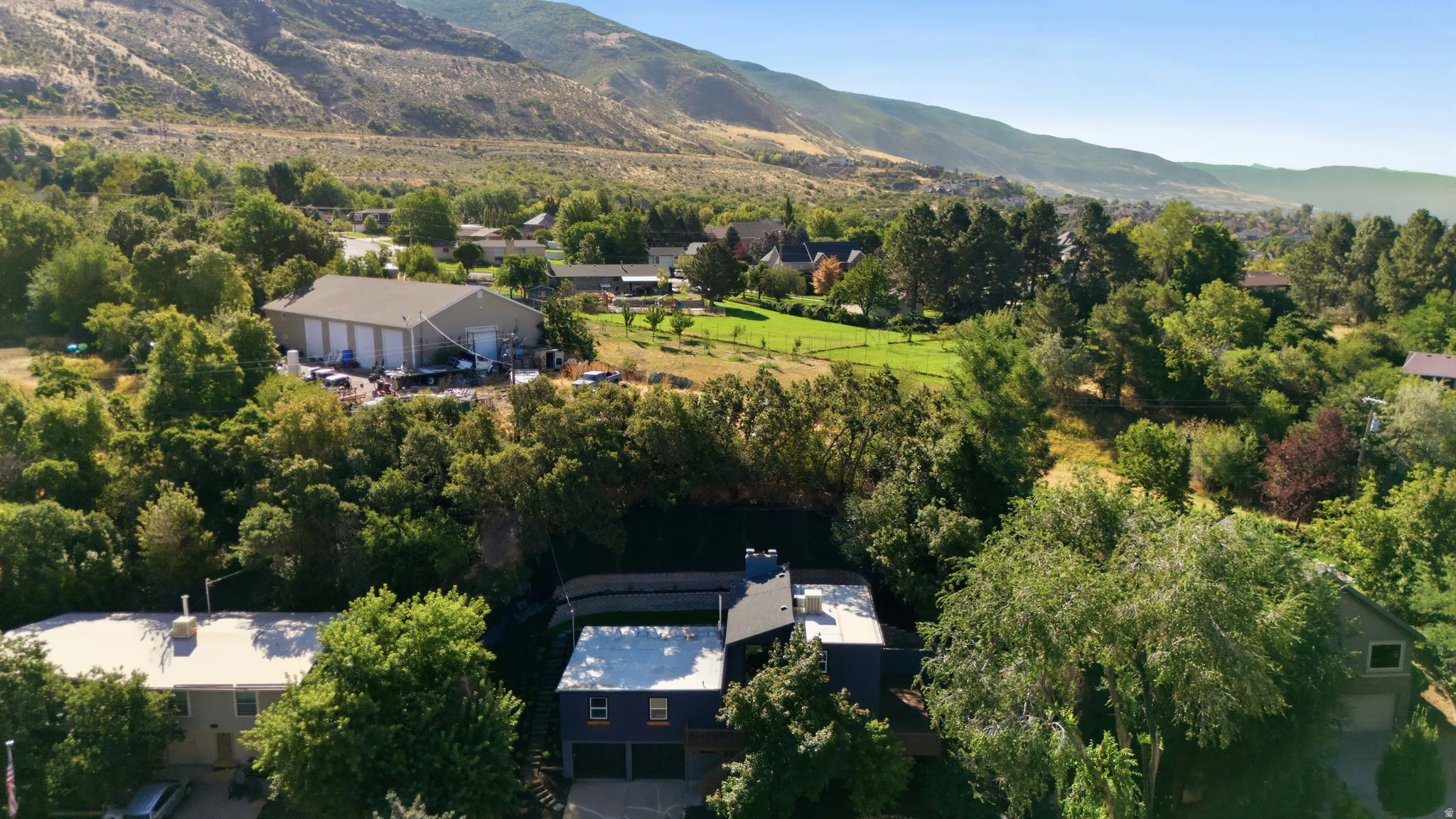 Aerial perspective showcasing the property's setting with surrounding mature trees and distant mountains
