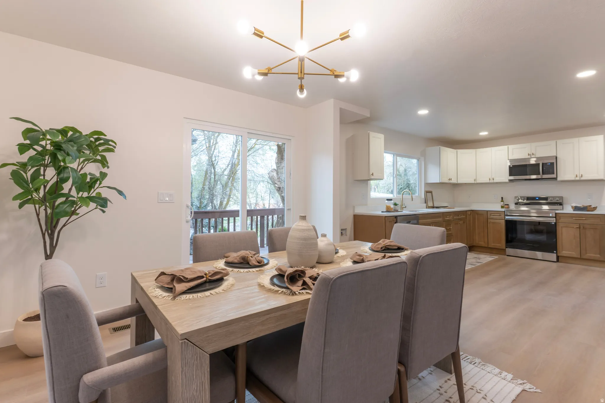 Open-concept dining area featuring a contemporary sputnik chandelier and wood-finish flooring