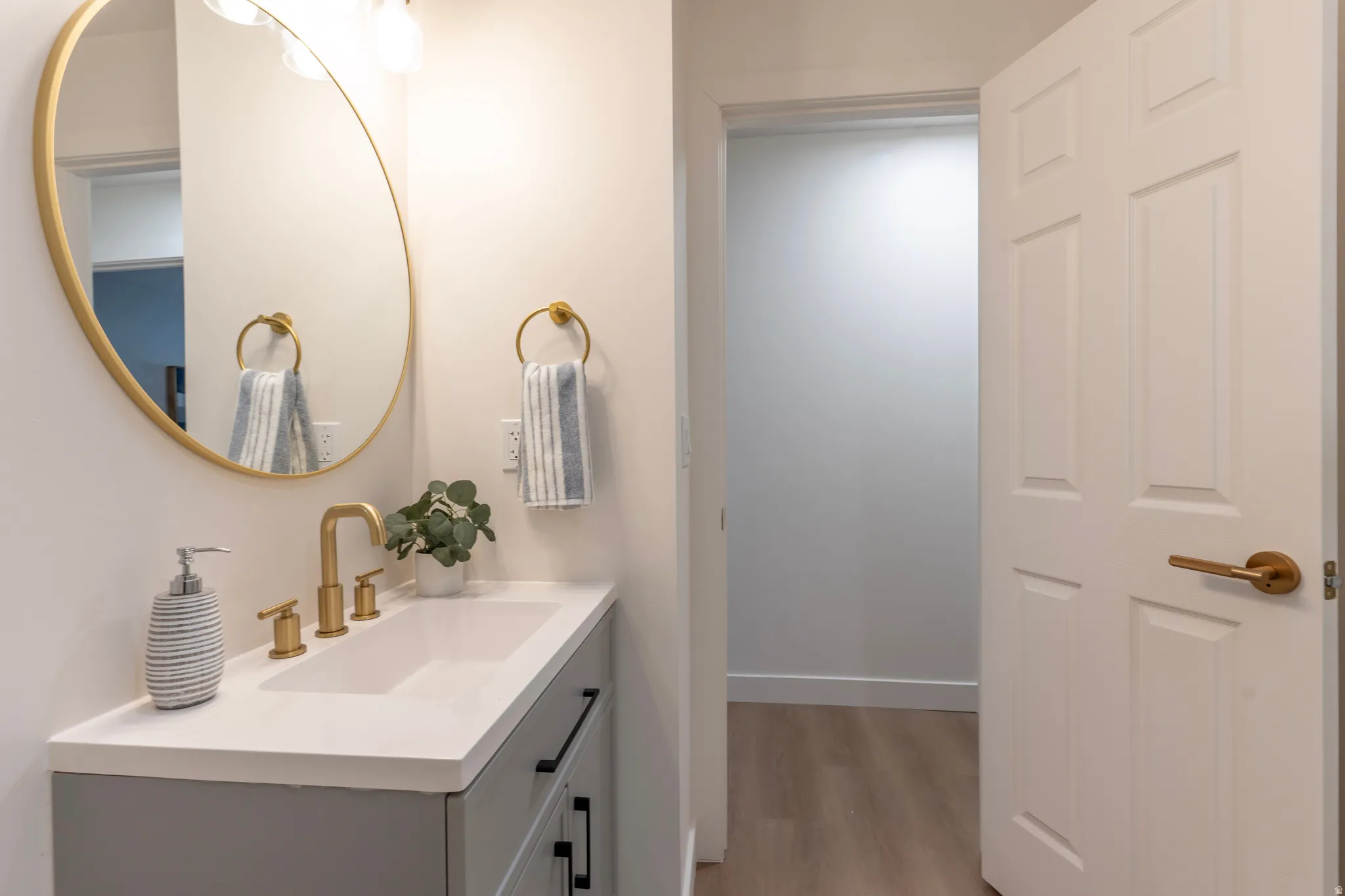 Vanity featuring a gold-framed mirror, integrated sink, gold-finish faucet, and a light-toned countertop