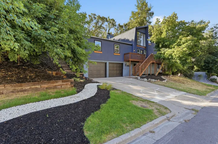 Contemporary exterior with blue siding, wood accent trim, a multi-level wood deck, and an attached two-car garage