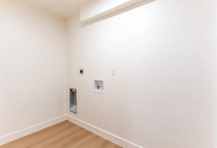 Laundry hookups with wood-finish flooring and neutral wall tones