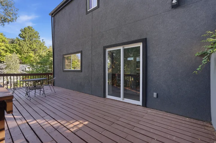 Expansive wood-plank deck with railing, featuring a sliding glass door and a rectangular window