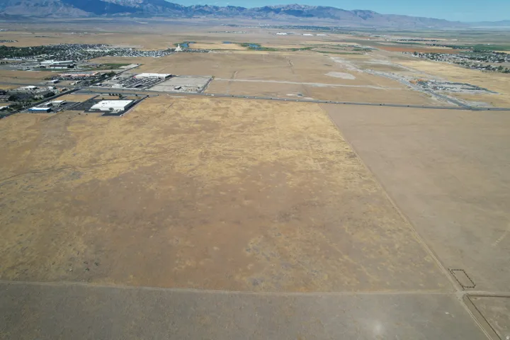 Expansive undeveloped land with distant mountain backdrop, featuring a flat topography and visible access roads