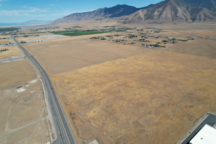Expansive open land with a multilane highway, mountainous terrain, and distant residential structures