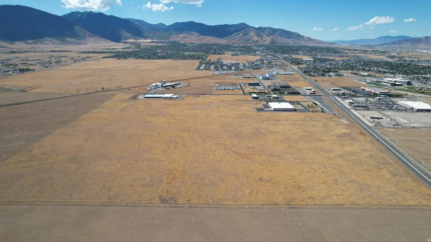 Expansive undeveloped land with a distant mountain range, bordered by roadways, and a developed area