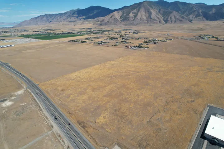 Expansive land parcel with surrounding mountain range and paved roadway access
