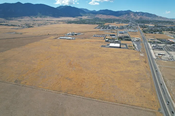 Expansive land parcel with surrounding commercial structures, highway access, and distant mountains