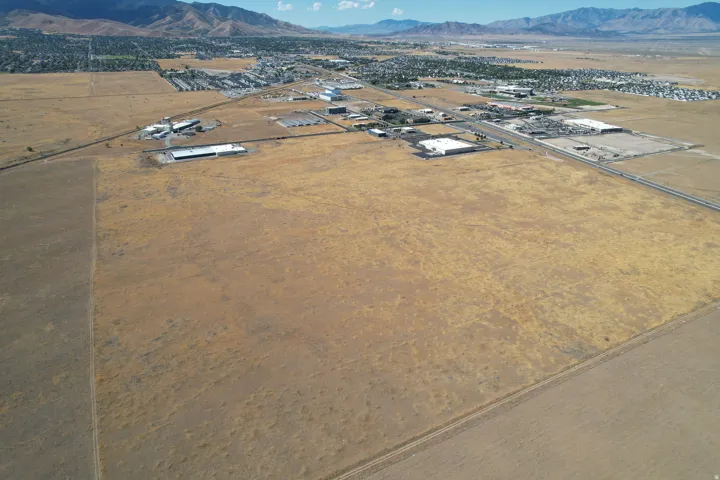 Expansive undeveloped land with distant mountain ranges and scattered commercial structures