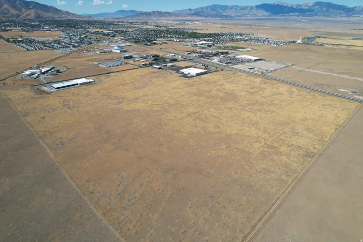 Expansive undeveloped land featuring a clear perimeter, adjacent to developed areas, with distant mountains