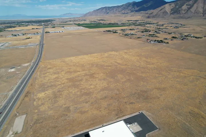 Expansive undeveloped land featuring a paved roadway and distant mountains