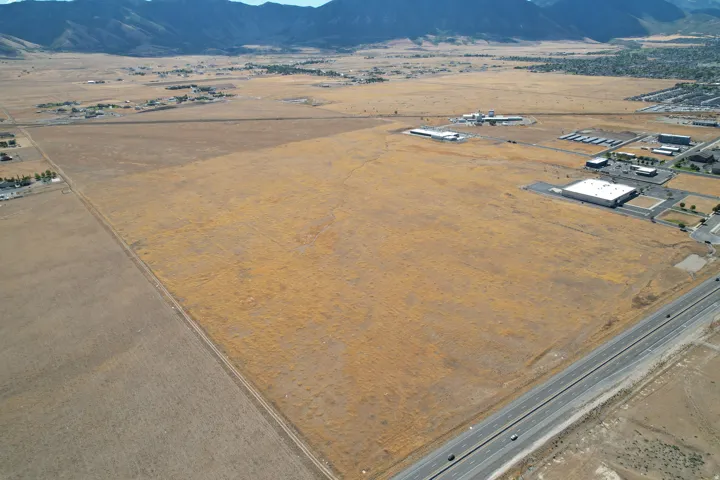 Expansive undeveloped acreage featuring a highway frontage, mountain backdrop, and surrounding commercial structures